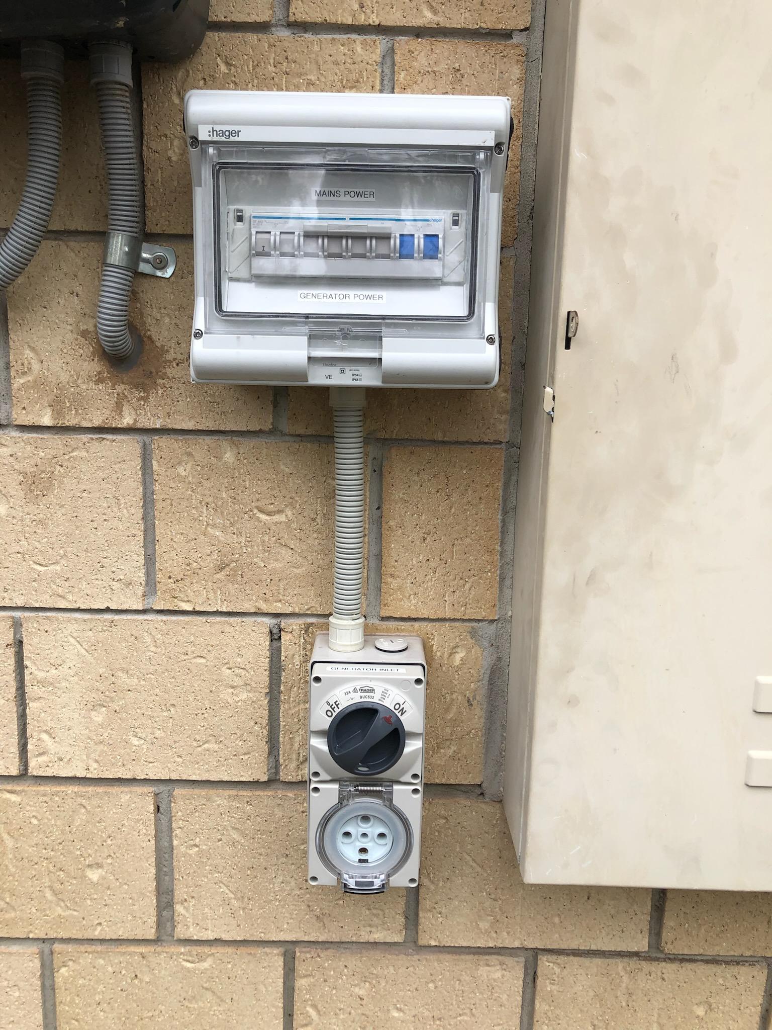 Weatherproof mains and generator changeover switch with outdoor outlet on a brick wall