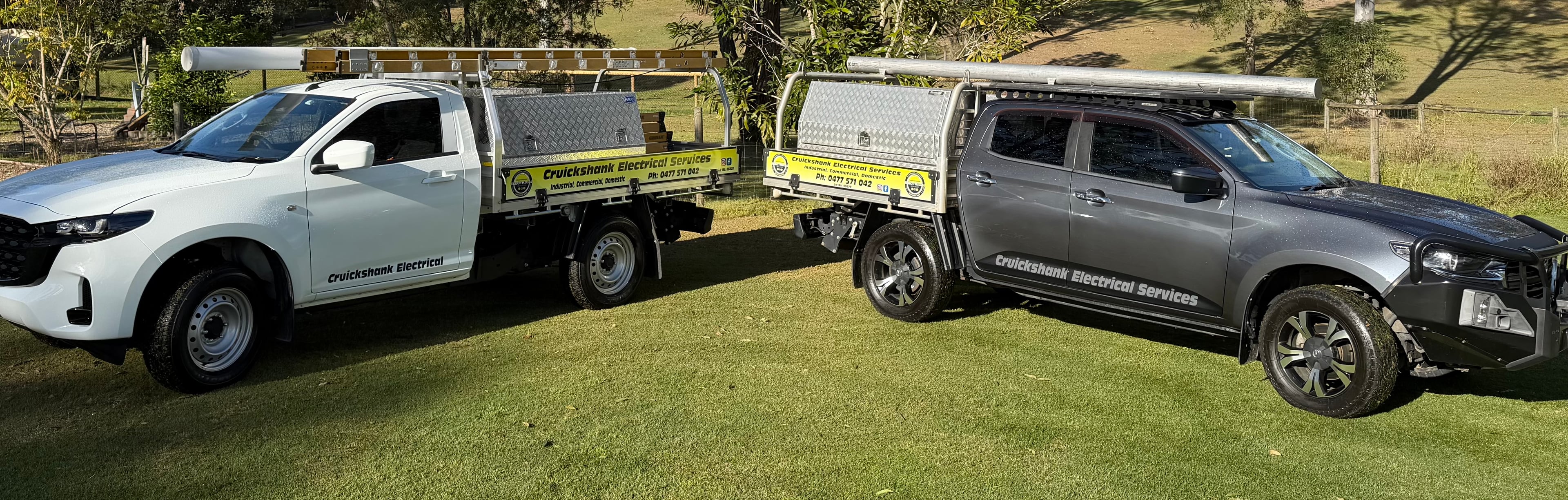 Cruickshank Electrical's two fully equipped work utes parked on a grassy property